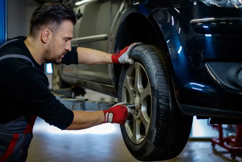 Mechanic putting lug nuts of tire back on