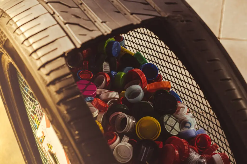 Recyled tire made in to a garbage with plastic bottle caps inside