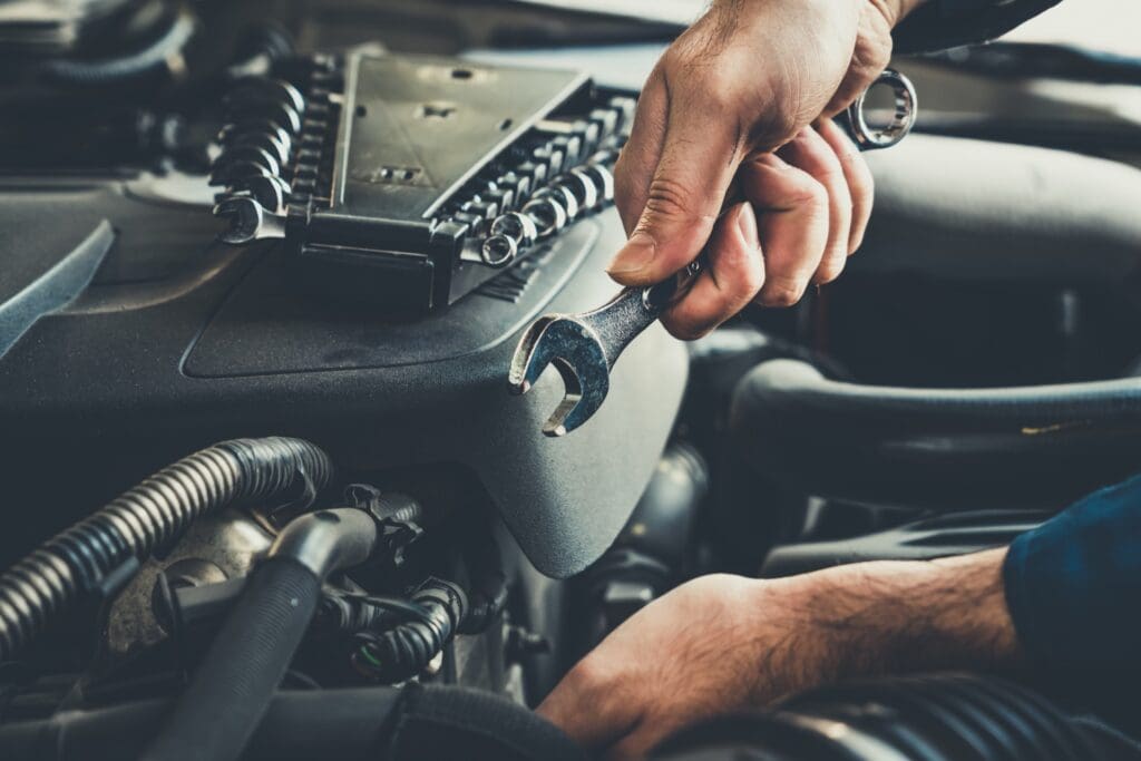 Mechanic using wrenches on car engine